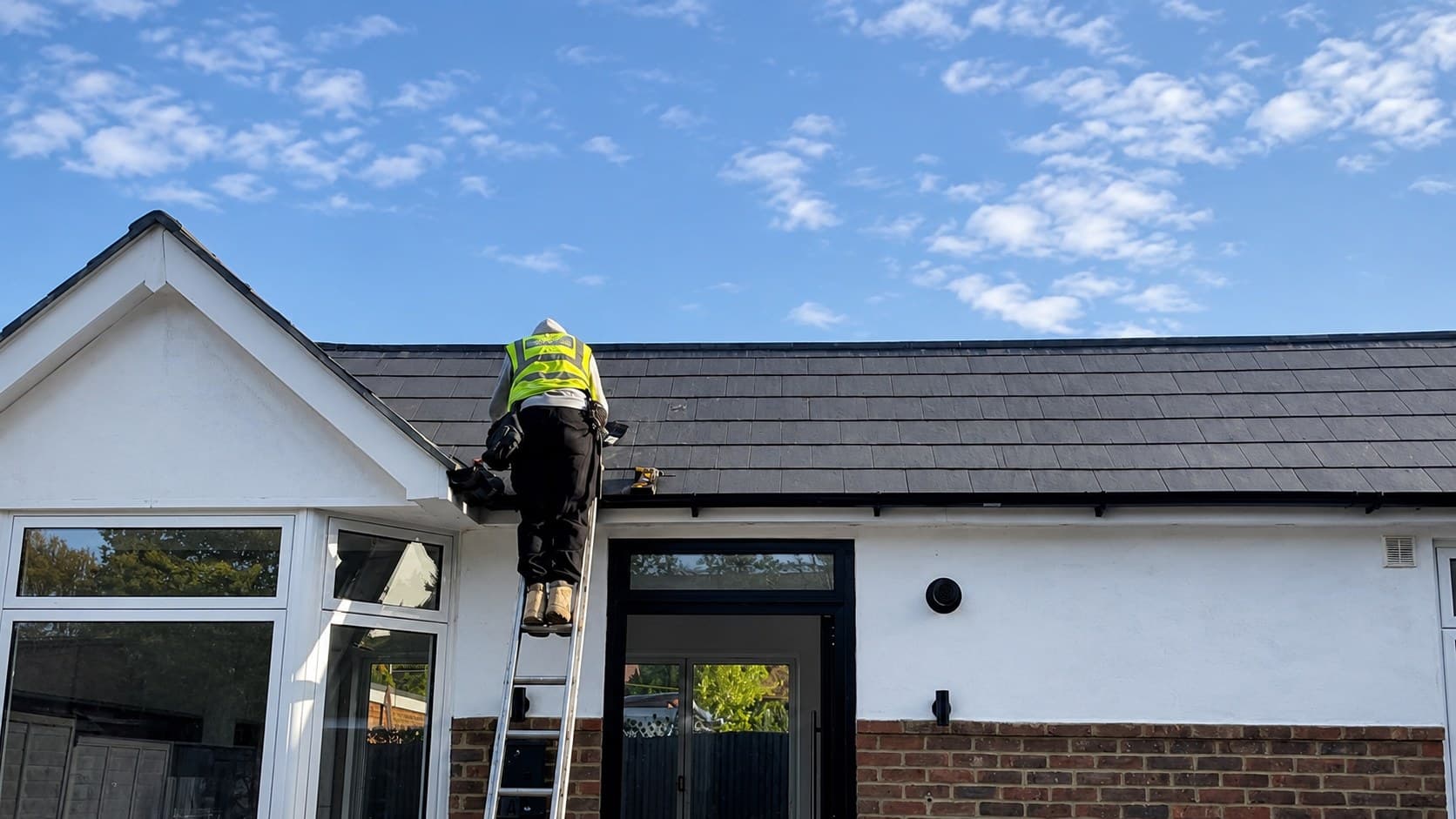 A Britannia Energy installer at work on a rooftop under a clear blue sky